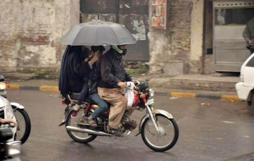 لاہور شہر میں ہونے والی بارش کے دوران شہری اپنی منزل کی جانب ..