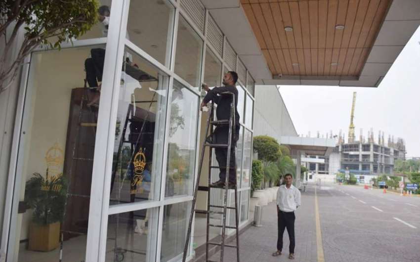 لاہور : ملازمین فلیٹیز ہوٹل کے داخلی راستے کے شیشے صاف کررہے ..