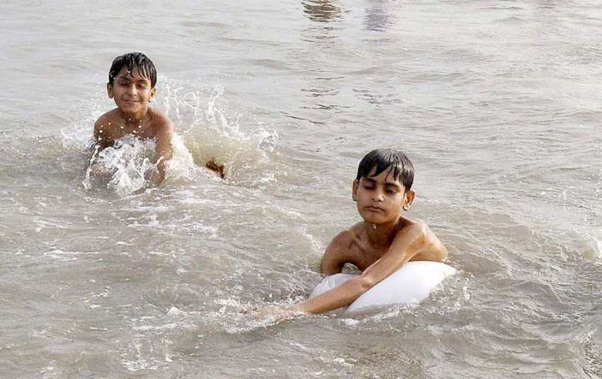 کراچی: بچے نیٹی جیٹی پل کے نیچے سخت گرمی میں نہار ہے ہیں۔ ..