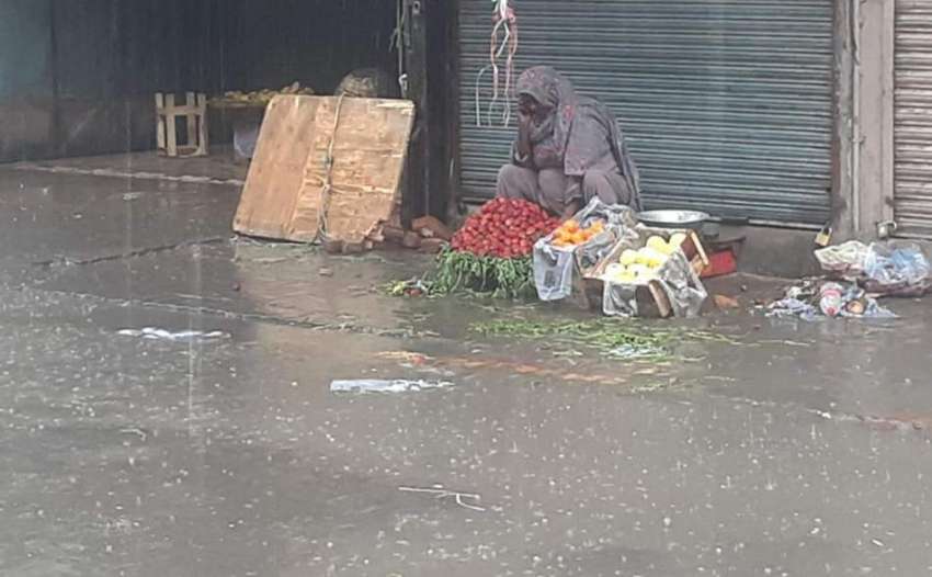 لاہور، شہر میں ہونے والی بارش کے دوران ایک محنت کش خاتون ..
