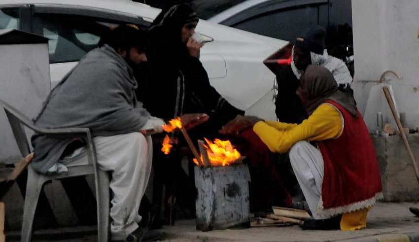 راولپنڈی، موسم سرد ہونے پر ڈھولچی سڑک کنارے آگ تاپ رہے ہیں۔