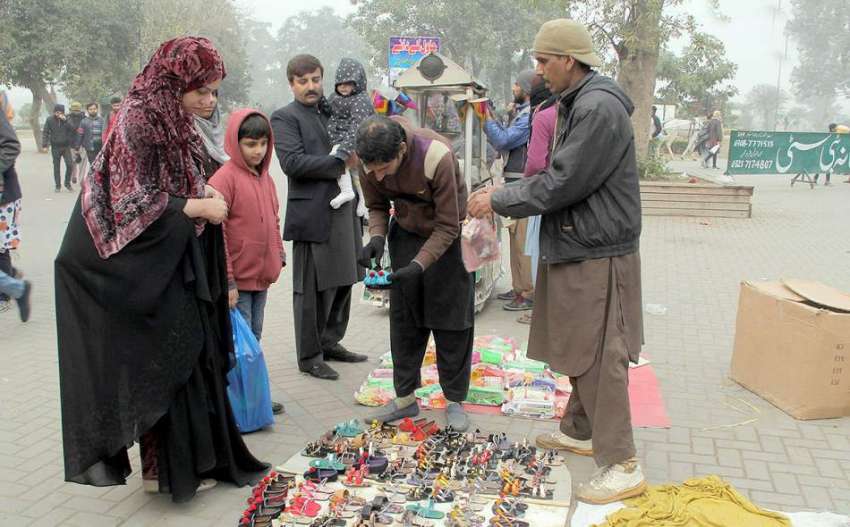 لاہور: گریٹر اقبال پارک میں ایک خاتون بچوں کے جوتے خریدنے ..