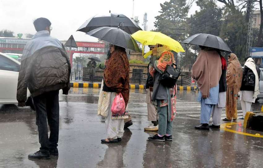 راولپنڈی: بس سٹاپ پر کھڑے شہری چھتری تانے گاڑی کا انتظار ..