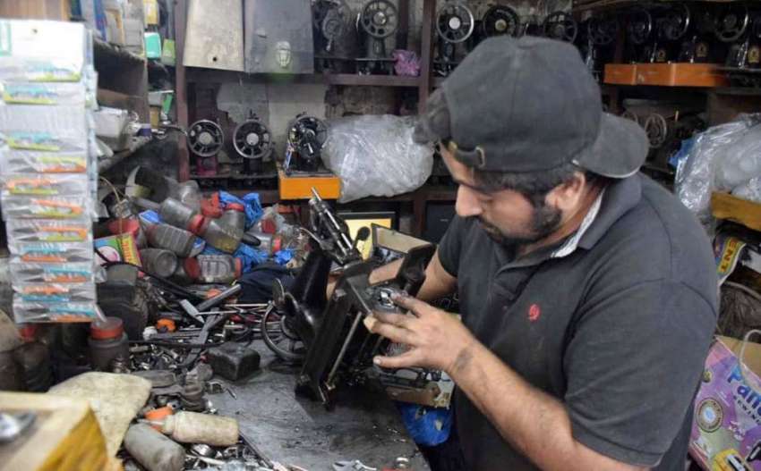 لاہور: ایک کاریگر سلائی مشین ٹھیک کر رہا ہے۔ 