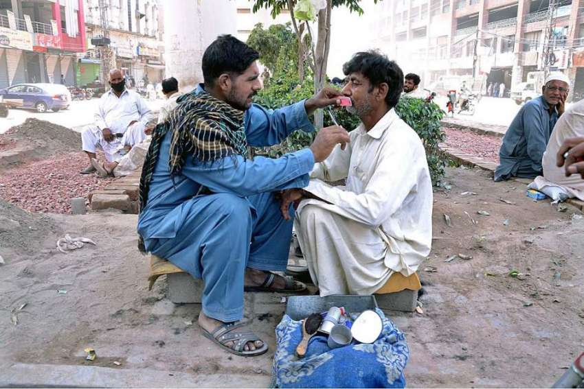 لاہور: لاک ڈاؤن کے دوران سڑک کے کنارے بیٹھا ایک حجام نے اپنے ..