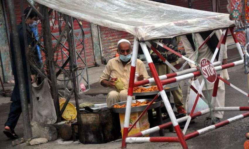 راولپنڈی، محنت کش بارش سے بچنے کیلئے پلاسٹک شیٹ لگائے روڈ ..