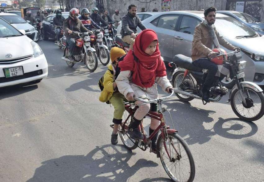 لاہور، ایک بچی چھوٹی سائیکل پر اپنے بھائی کو بٹھا کر اکیڈمی ..