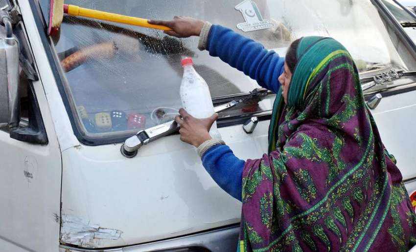لاہور، سگنل پر ایک محنت کش بچی گاڑی کی سکرین صاف کر رہی ہے۔