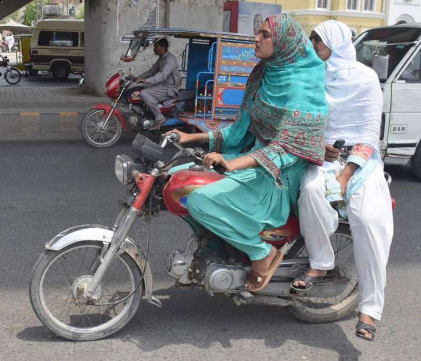 لاہور، دو خواتین موٹرسائیکل پر اپنی منزل کی جانب گامزن ہیں۔