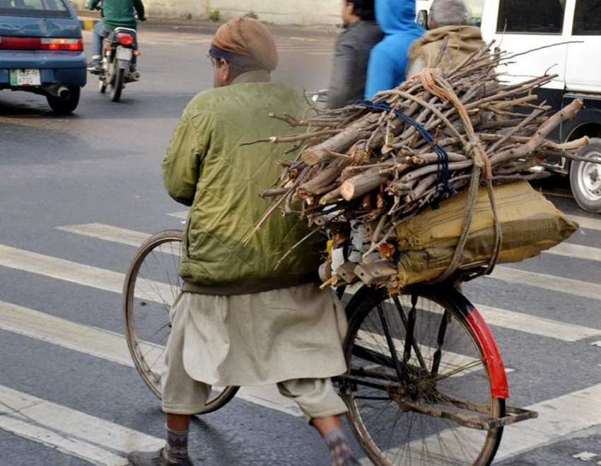 لاہور، ایک محنت کش جلانے کیلئے لکڑیاں سائیکل پر رکھے جا ..