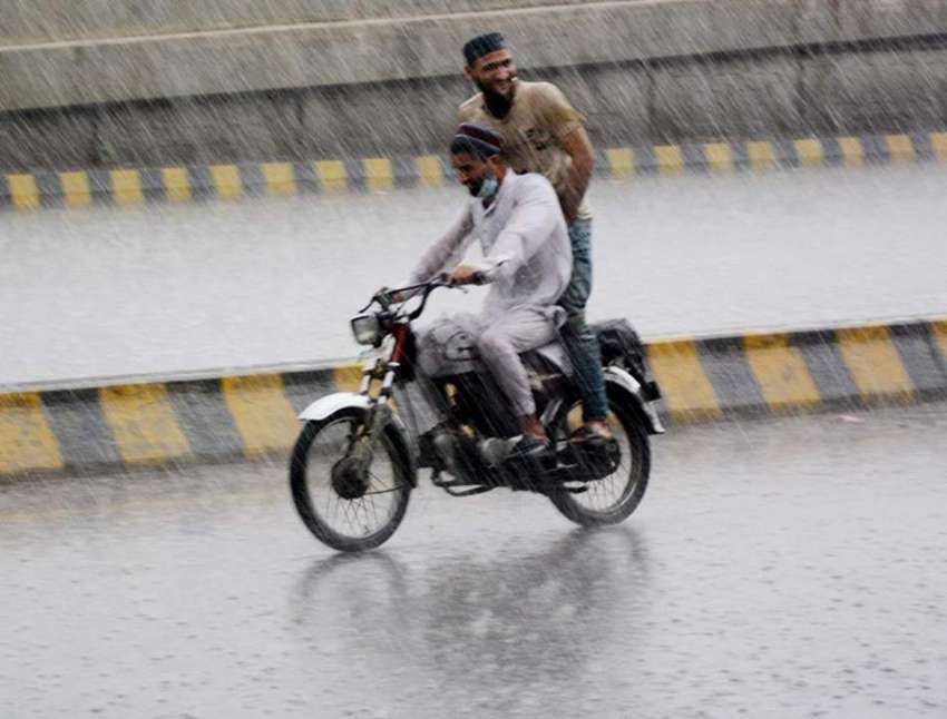 لاہور، موٹرسائیکل سوار بارش میں اپنی منزل کی جانب گامزن ..