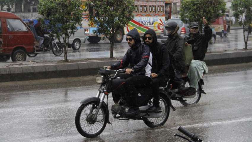کراچی، موسم سرما کی پہلی بارش کے دوران موٹر سائیکل سوار ..