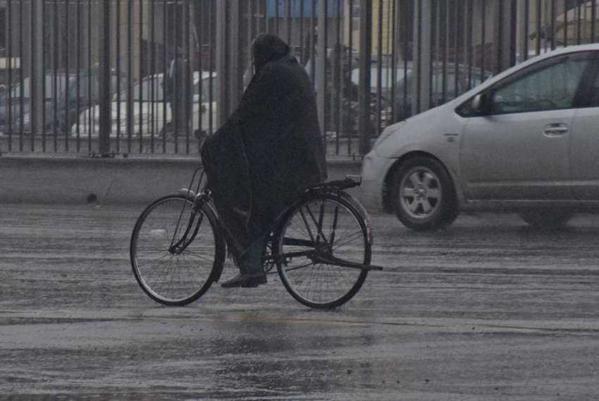 لاہور، شہر میں ہونے والی بارش کے دوران ایک شہری سائیکل پر ..