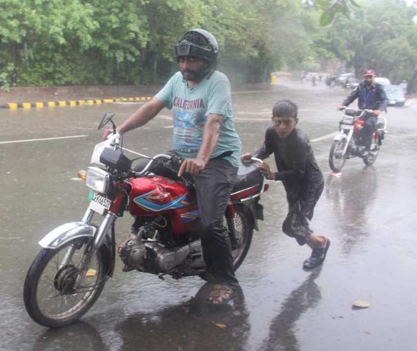 لاہور، شہری بارش میں بند ہونے والی موٹرسائیکل کو بچے سے ..