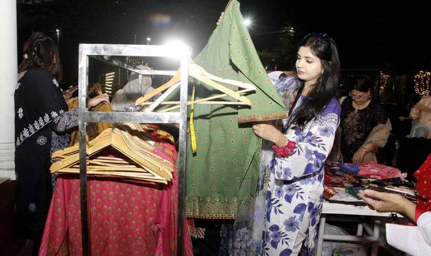 لاہور، مقامی لیڈیز کلب میں سٹال سے ایک خاتون کپڑے خریدنے ..