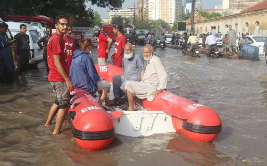 کراچی، ٹاور پر ایدھی رضاکار بزرگ شہریوں کو بارش کے پانی ..