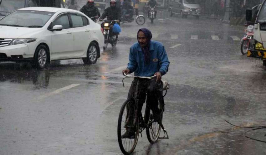 لاہور، ایک سائیکل سوار شخص بارش کے دوران اپنی منزل کی جانب ..