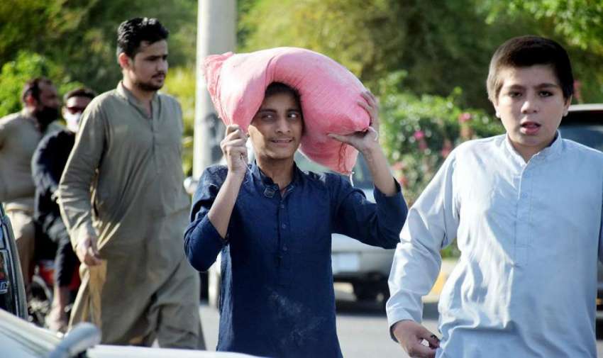 لاہور، شادمان رمضان بازار سے بچے آٹا خرید کر لے جا رہے ہیں۔