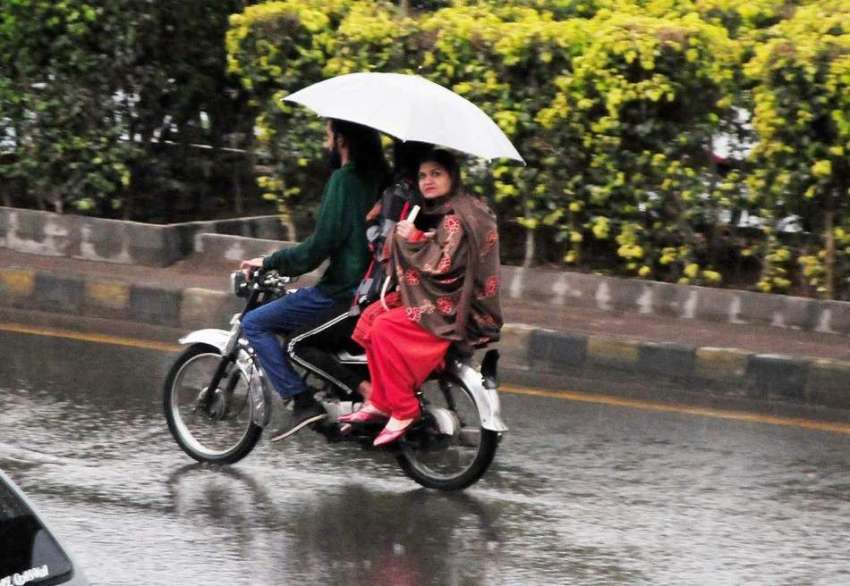 راولپنڈی، مری روڈ پر بارش سے بچنے کیلئے ایک موٹرسائیکل سوار ..