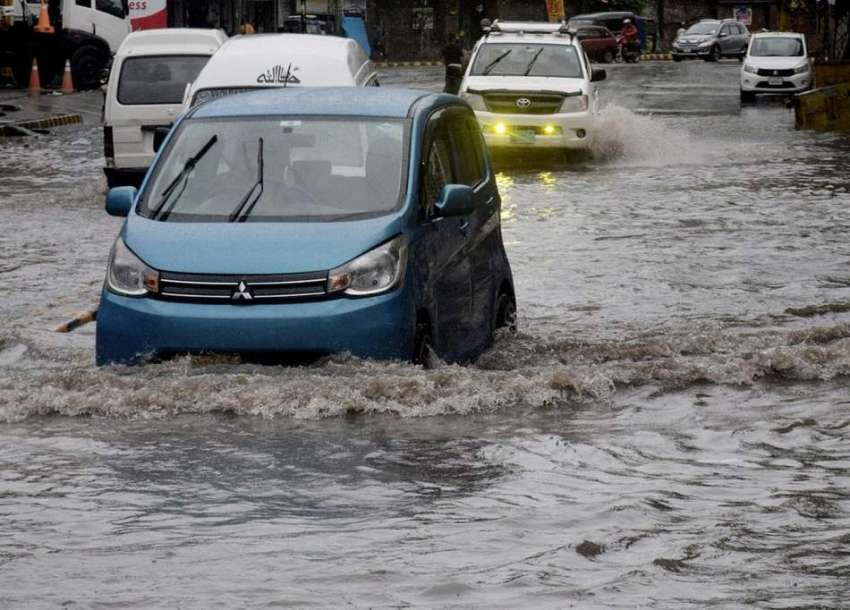 لاہور، موسلادھار بارش کے بعد سڑک پر جمع پانی سے گاڑیاں گزر ..
