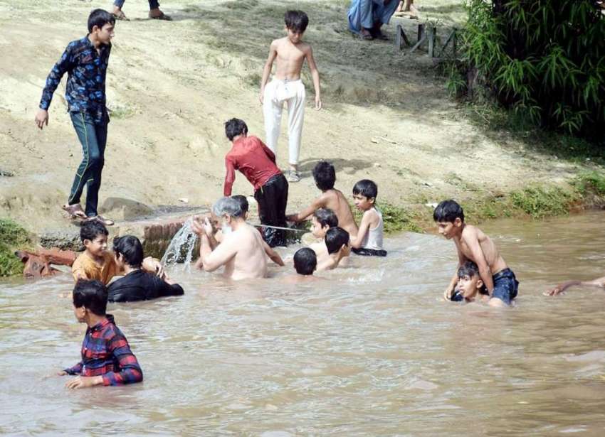 لاہور، بچے گرمی کی شدت کم کرنے کیلئے نہر میں نہا رہے ہیں۔