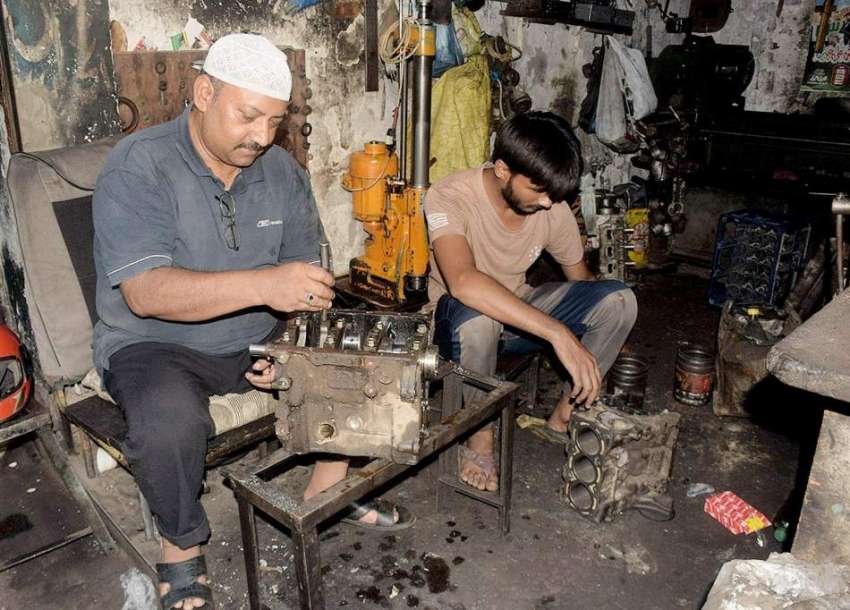 لاہور، کاریگر گاڑی کا انجن مرمت کرنے میں مصروف ہیں۔