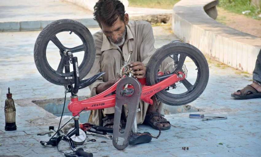 لاہور، نیلاگنبد میں کاریگر سائیکل مرمت کرنے میں مصروف ہے۔