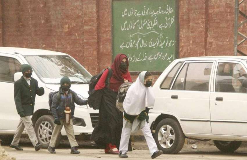 لاہور، ایک خاتون صبح کے وقت شدید سردی میں بچوں کو سکول چھوڑنے ..