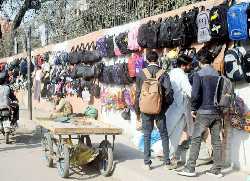 لاہور، نوجوان سڑک کنارے فٹ پاتھ پر سجی دکان سے بیگ خرید رہے ..