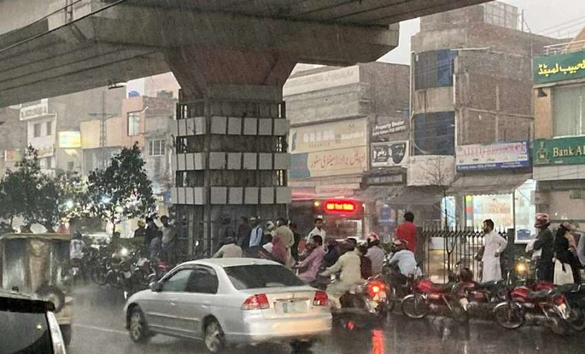 لاہور، شہری بارش سے بچنے کیلئے میٹروبس کے پل کے نیچے کھڑے ..