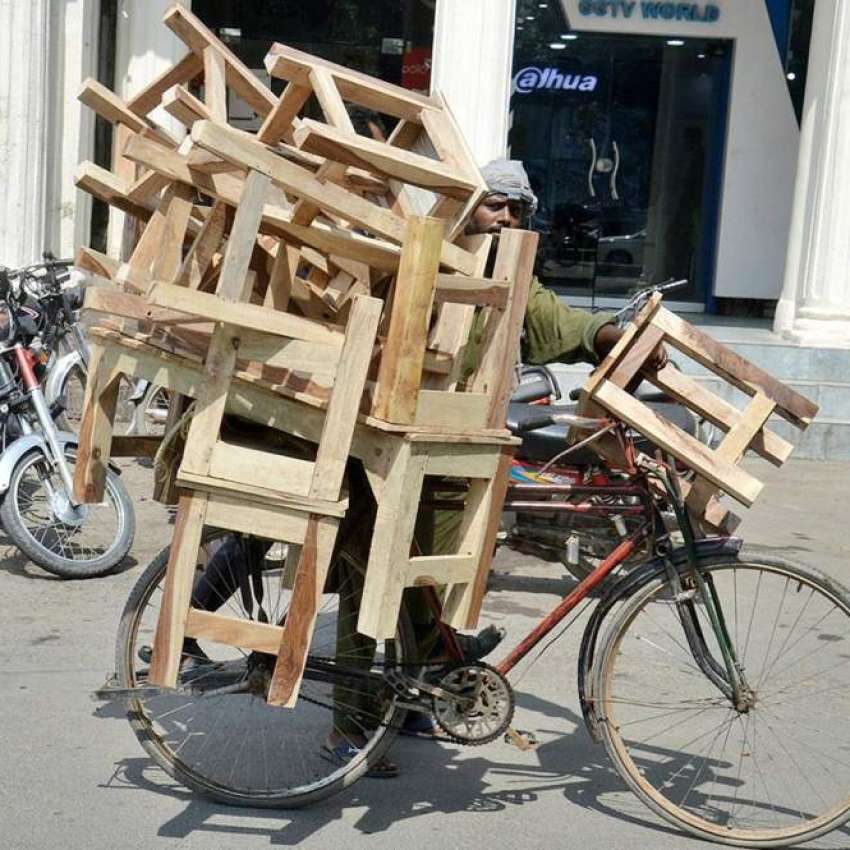 لاہور، محنت کش سائیکل پر لکڑی سے بنے بنچ اور سٹول فروخت کر ..