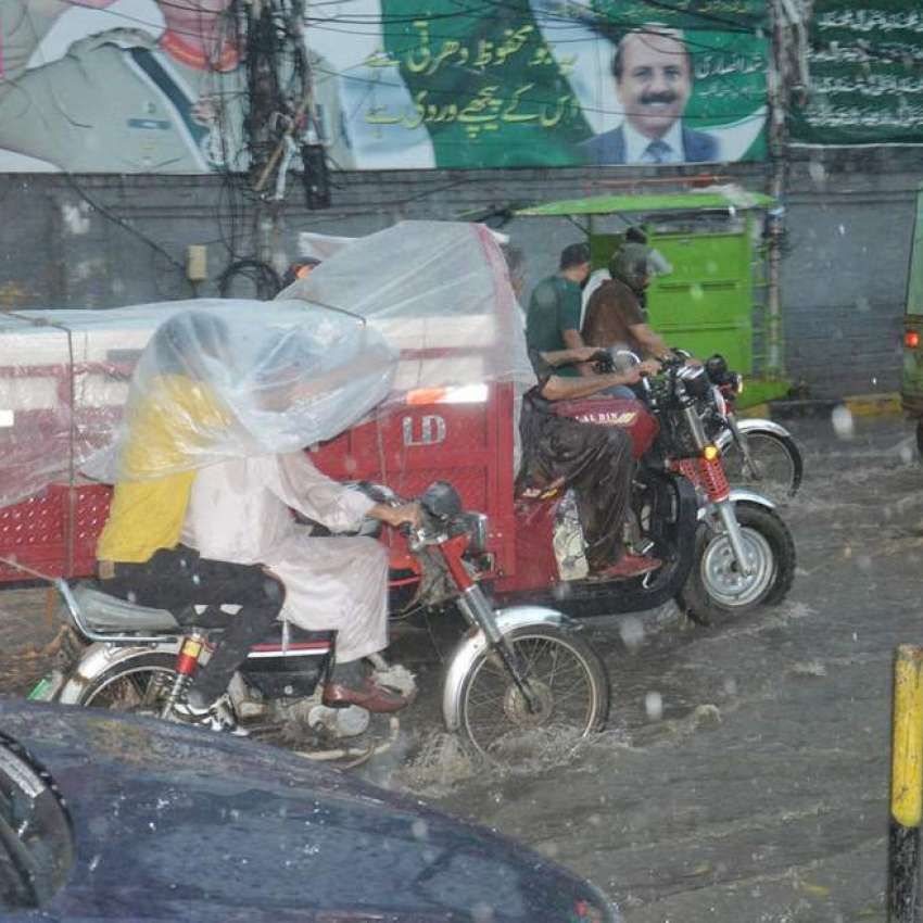 لاہور، شہری موسلا دھار بارش کے دوران اپنی منزل کی جانب رواں ..